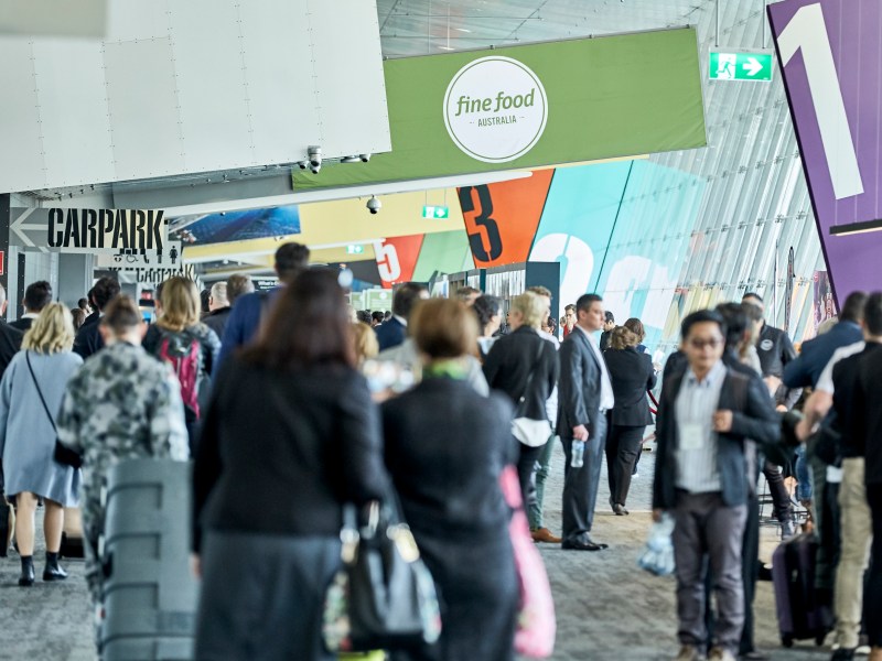 A crowd walking through a corridor at an expo.
