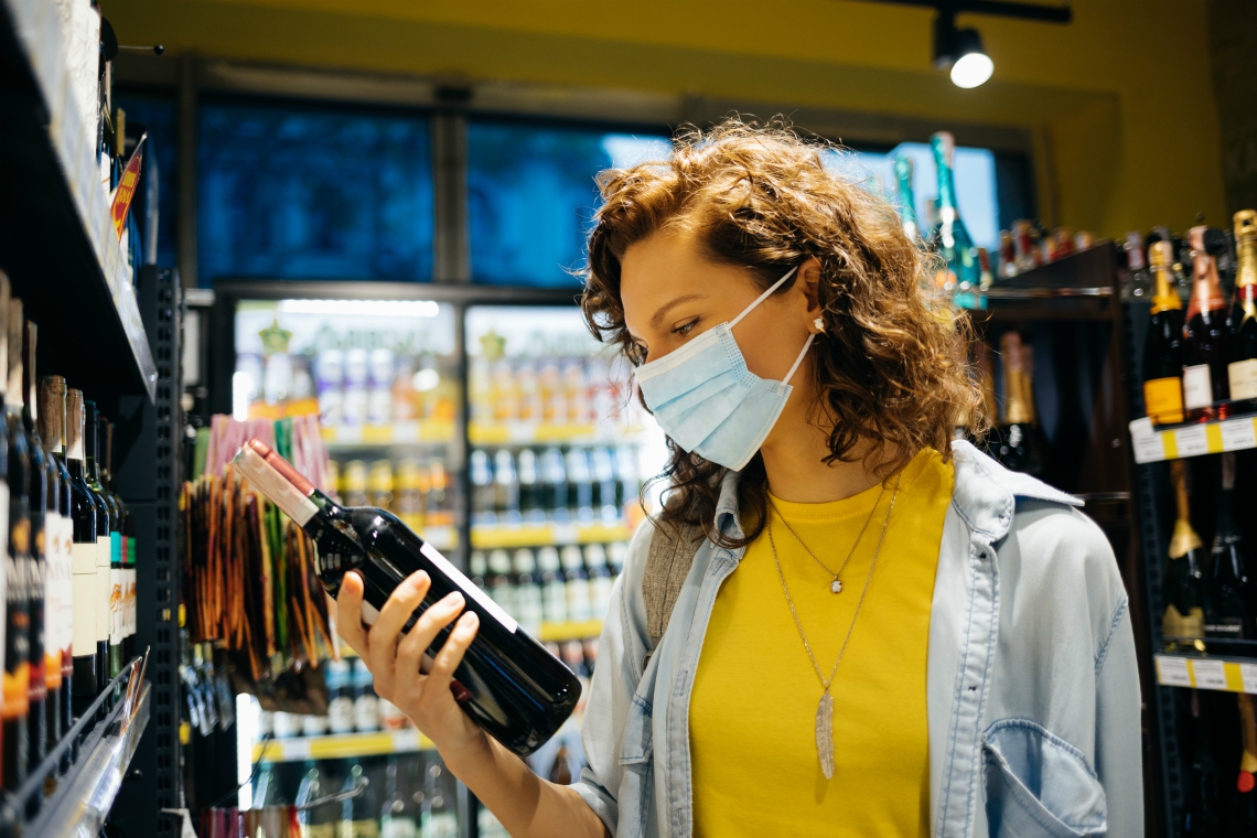 retail restrictions lockdwon - customer wears mask while choosing wine