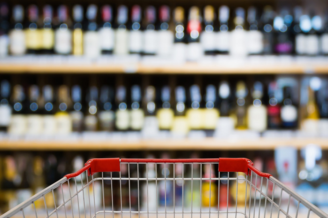 Shopping cart view with Abstract blur wine bottles on liquor alcohol shelves in supermarket or wine store background retail