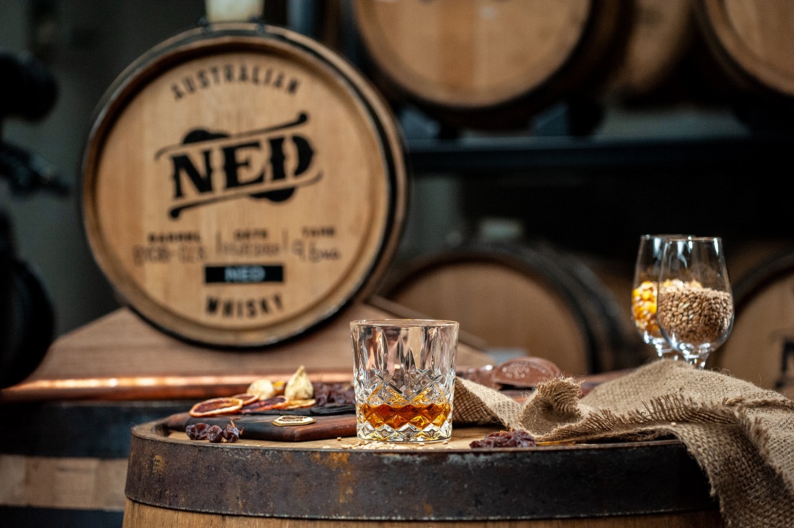 NED Australian spirits - glass on table with barrels in background