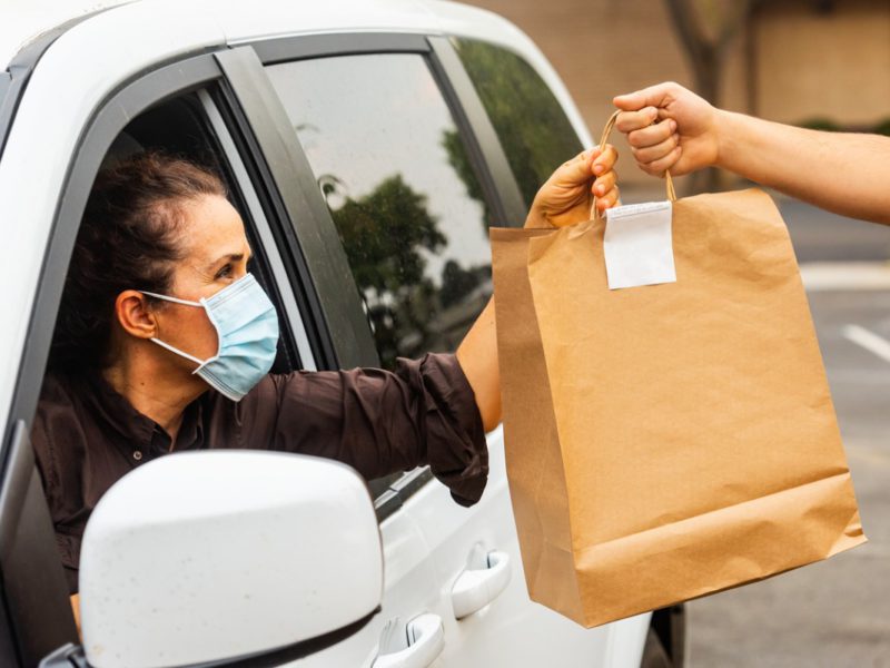 A woman collects her food delivery whilst wearing a mask