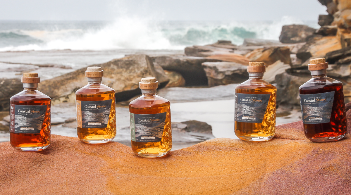 Coastal Stone range of whisky bottles at a beach with crashing waves in background