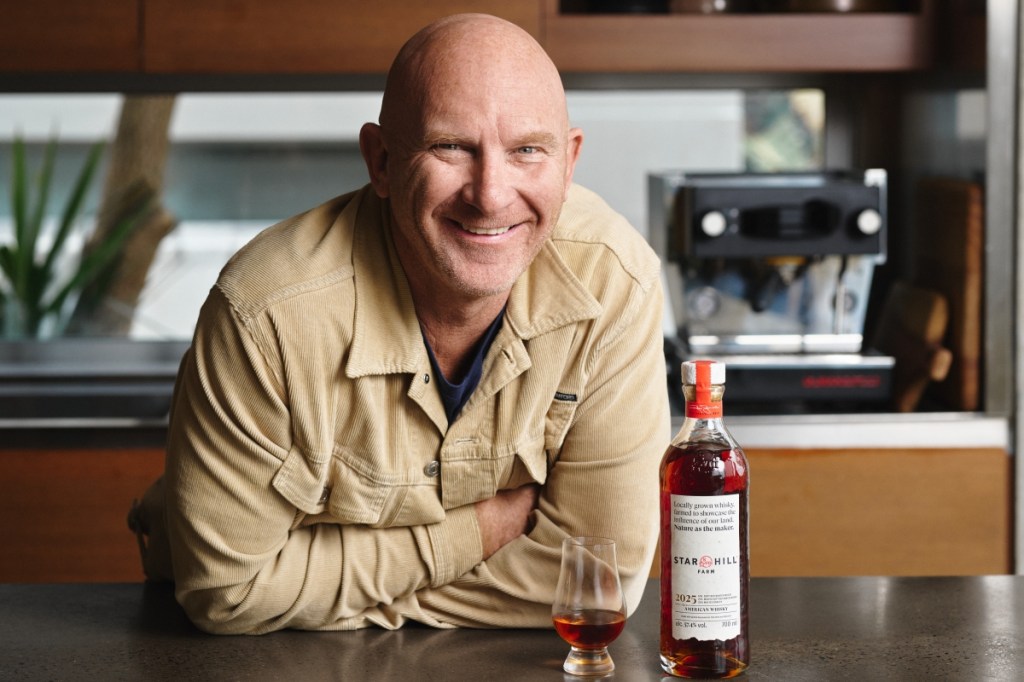 Matt Moran leaning down next to a bottle and glass of Star Hill Farm Whisky.